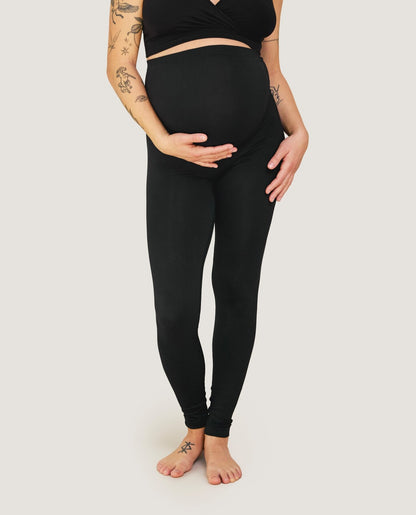 Schwangere Frau trägt schwarze nahtlose Carriwell-Leggings mit Stützeinsatz über dem Bauch